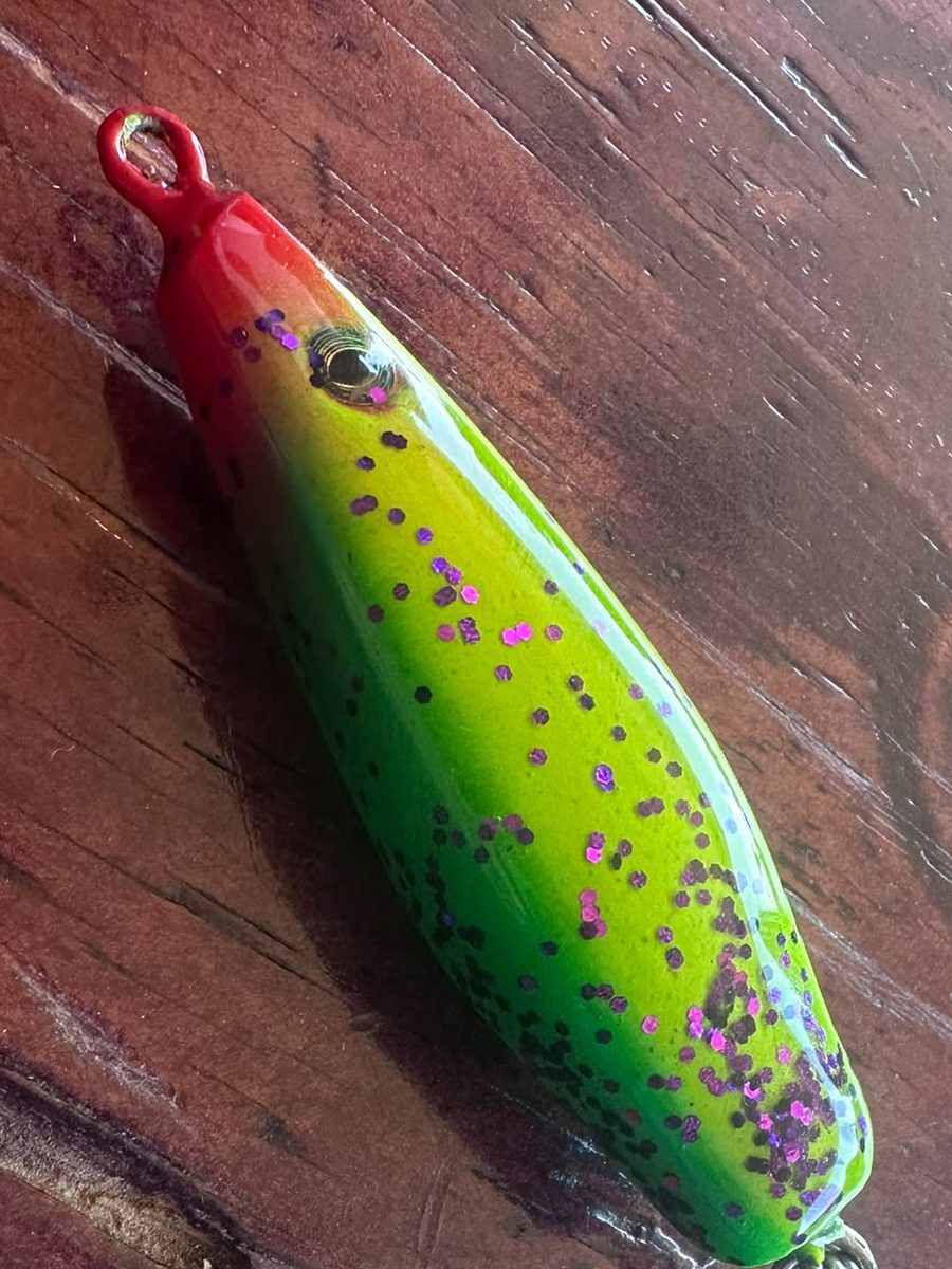 Proto 01 on the workshop wood bench — red head, 3D eye, treble hook