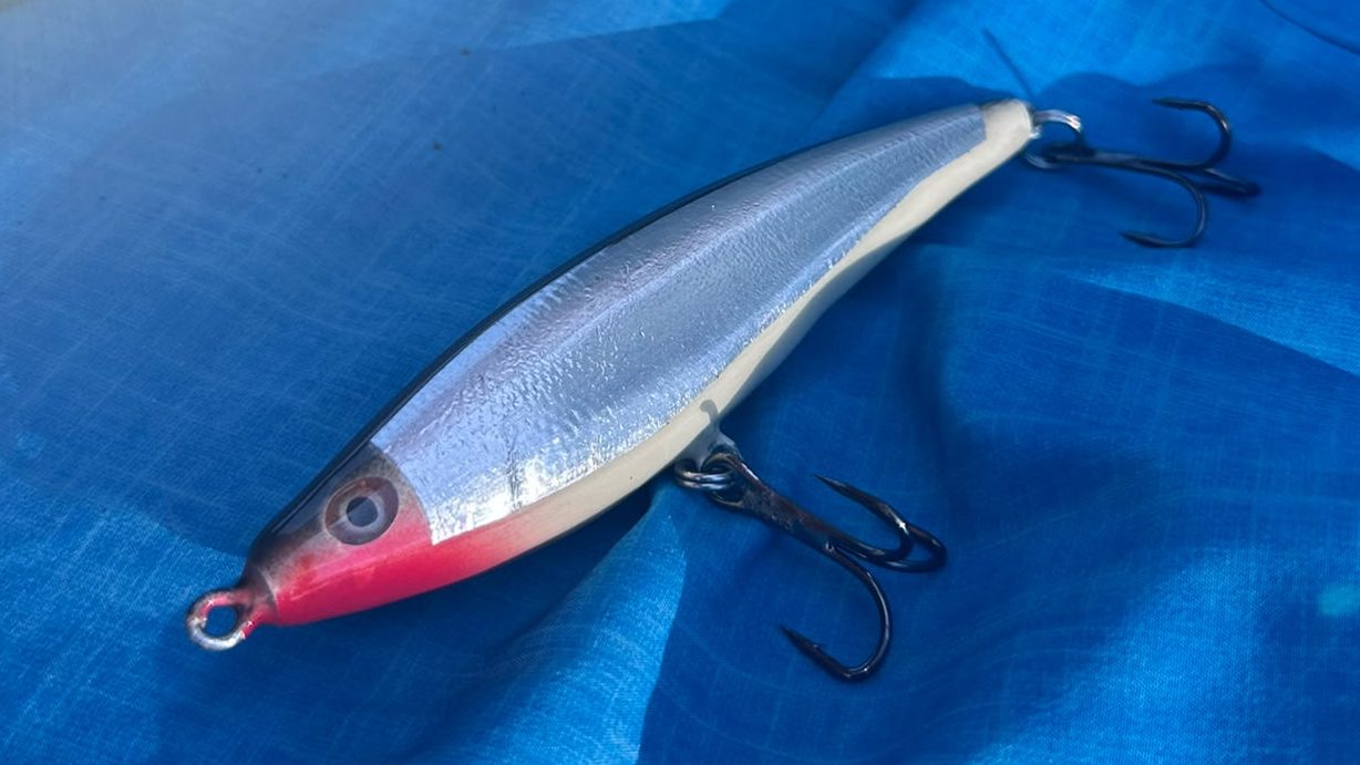 Proto 02 — silver foil, black back, red head, two trebles, on the boat deck